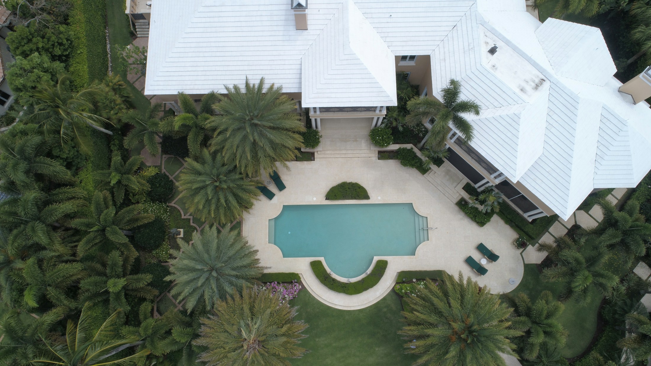 Aerial view of a Naples home with a pool courtyard and palm trees